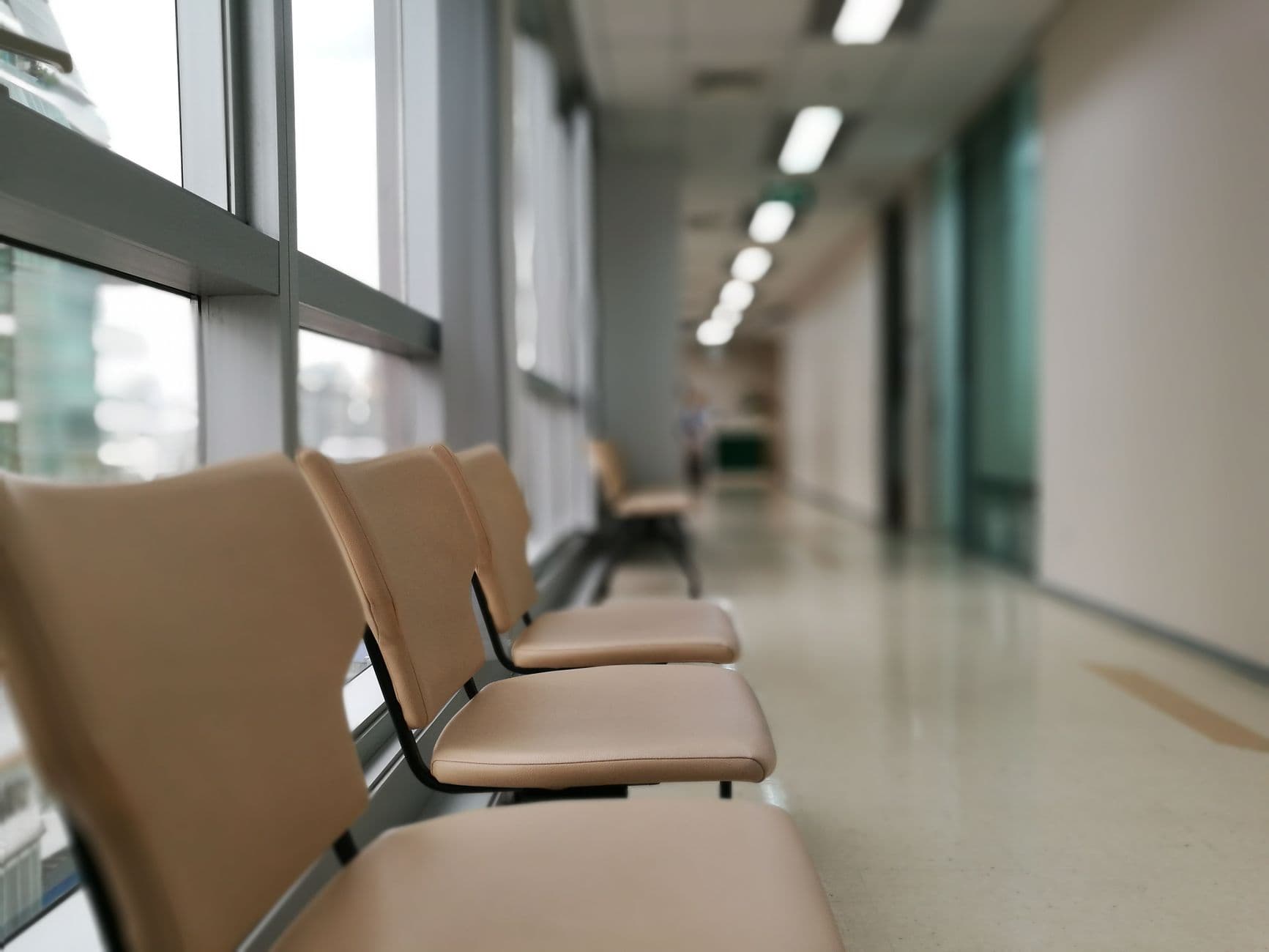 Række tomme stole i hospitalsgang med dæmpet lys